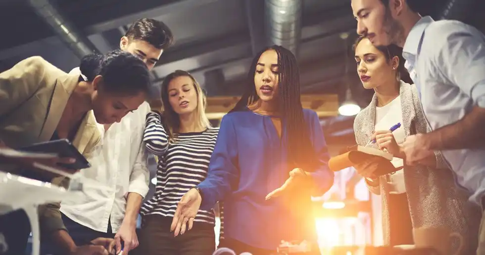 Fotografía de líder empresarial con su equipo realizando una lluvia de ideas, fomentando la creatividad e innovación empresarial. 