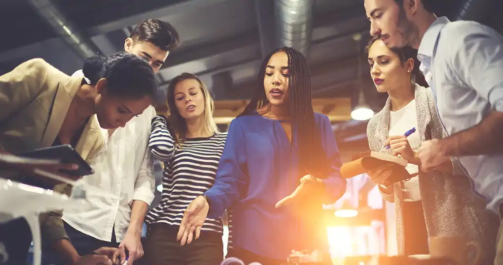 Fotografía de líder empresarial con su equipo realizando una lluvia de ideas, fomentando la creatividad e innovación empresarial.