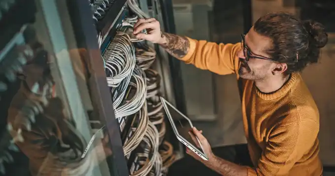 Un hombre trabaja en el cableado de servidores.