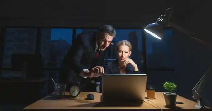 Dos personas en traje de negocios trabajando en una computadora portátil