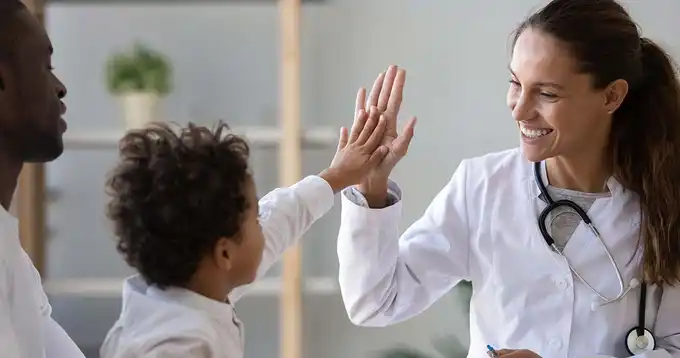 Un médico celebra con un niño dándole un choca esos cinco 