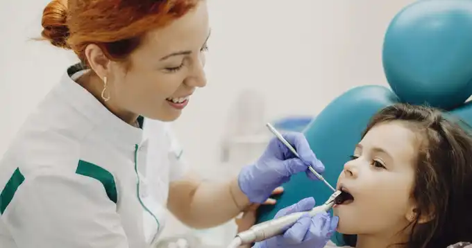 Una joven odontóloga atiende a un niño pequeño en la sala de consultorio