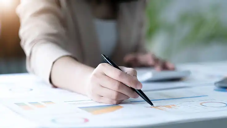 Imagen de un profesional aplicando sus conocimientos obtenidos en una maestría en tributación fiscal, al hacer cálculos numéricos en un escritorio